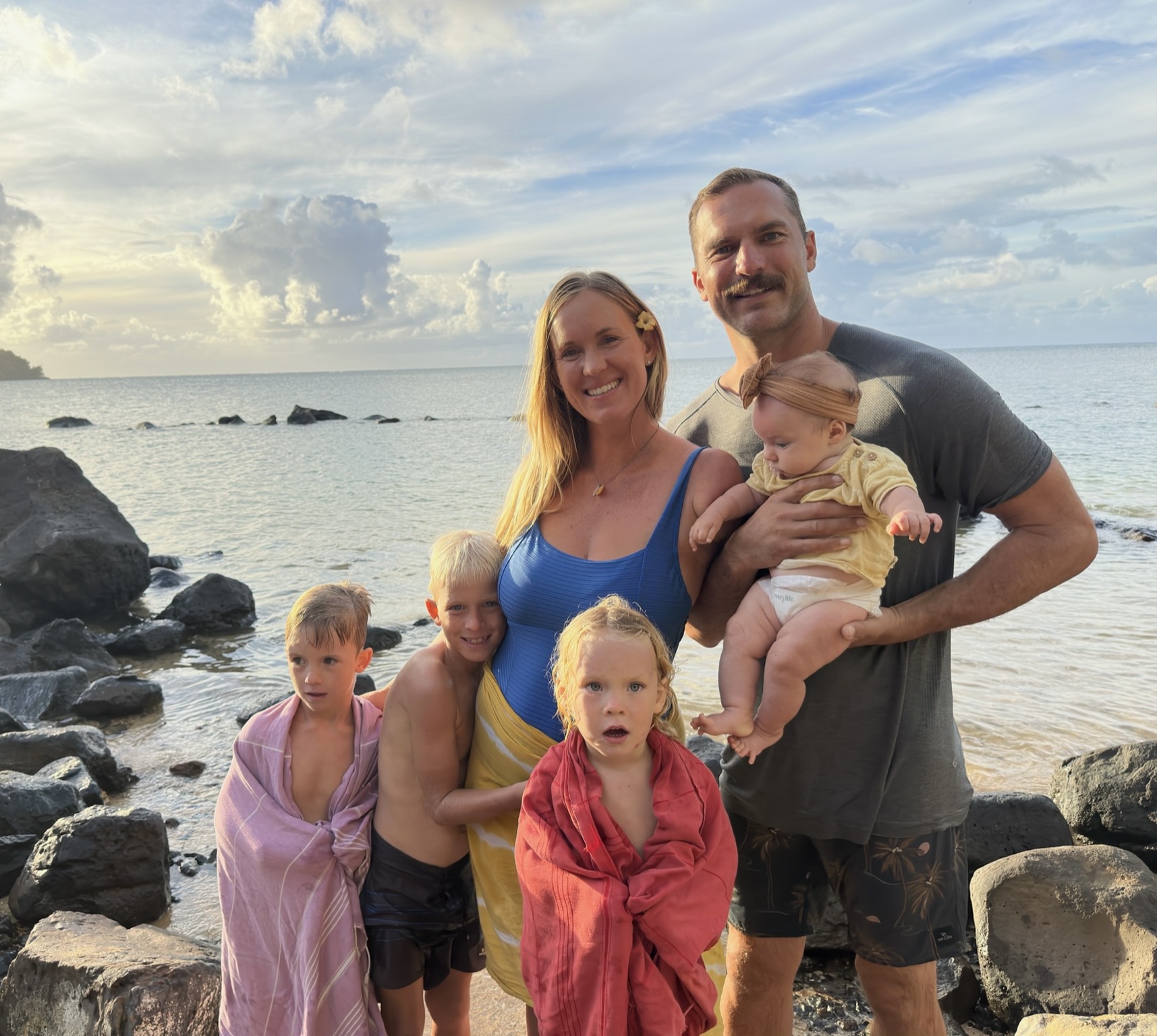 Bethany's family poses by the beach with their newborn daughter